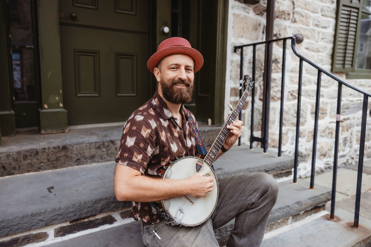 Jason Vance sitting on a stoop playing banjo
